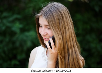 Beautiful Teen Girl Talking On The Phone Outdoors In The Park