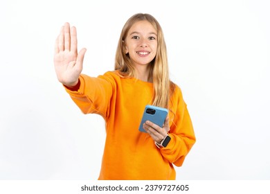 Beautiful teen girl using and texting with smartphone with open hand doing stop sign with serious and confident expression, defense gesture - Powered by Shutterstock