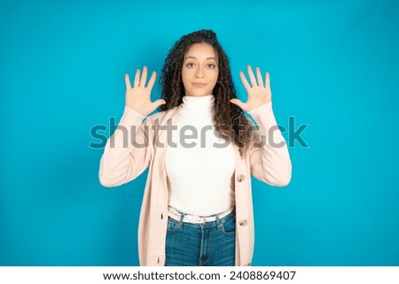 Beautiful teen girl wearing casual clothes showing and pointing up with fingers number ten while smiling confident and happy.