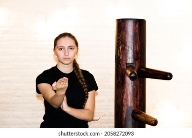 A 
beautiful teen girl, woman sportswoman athlete engaged in Wushu, training   traditional wing chun near  wooden dummy, doing Yongchunquan standard routines Duan forms. - Powered by Shutterstock