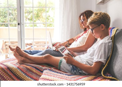 Beautiful Teen Reading New Trend Stories Online On Tablet With Mum. Technology Addicted Young Boy Watching Social Video At Home With His Mother. Child And Mommy Communicate And Plays With Tech Device.