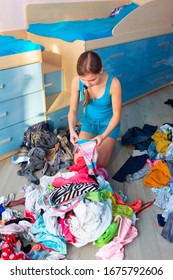 Beautiful Teenage Girl Folding Her Clothes In A Messy Bedroom