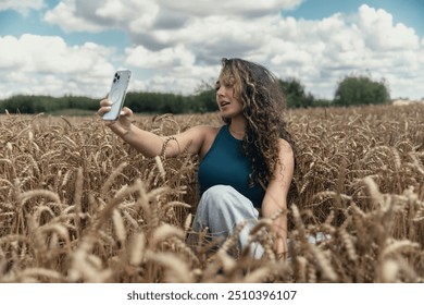 A beautiful teenage girl with long curly hair is taking a selfie on her smartphone in a wheat field. - Powered by Shutterstock