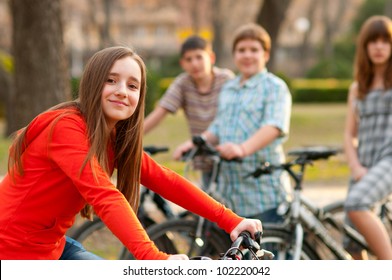 Beautiful teenage girl spending time with her friends riding bicycles.