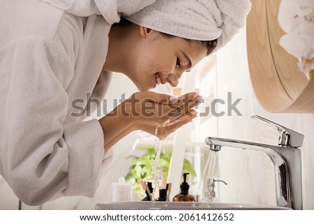 Beautiful teenage girl washing face with cleansing foam in bathroom. Skin care cosmetic
