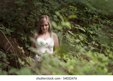 beautiful teenage girl wearing white flowy dress in forest