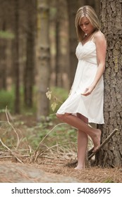 beautiful teenage girl wearing white flowy dress in forest
