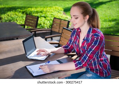 beautiful teenage student or school girl doing her homework in summer park
