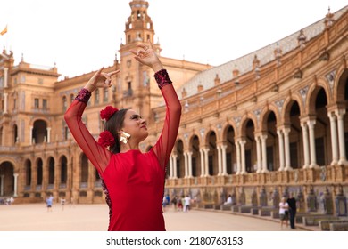 Beautiful teenage woman dancing flamenco in a square in Seville, Spain. She wears a red dress with ruffles and dances flamenco with a lot of art. Flamenco cultural heritage of humanity. - Shutterstock ID 2180763153