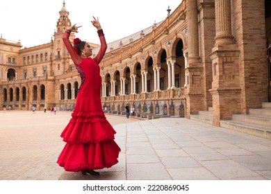 Beautiful teenage woman dancing flamenco in a square in Seville, Spain. She wears a red dress with ruffles and dances flamenco with a lot of art. Flamenco cultural heritage of humanity. - Shutterstock ID 2220869045