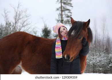 Beautiful teenager girl hugging brown horse in winter forest - Powered by Shutterstock