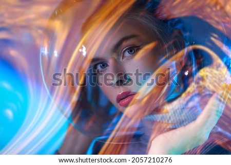 Beautiful tender girl looking through her glass spacesuit against the background of outer space. Space concept. 
