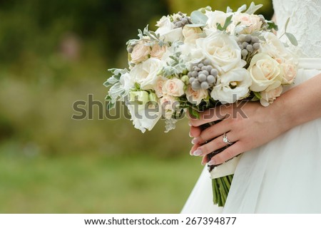 beautiful tender wedding bouquet of cream roses and eustoma flowers in hands of the bride