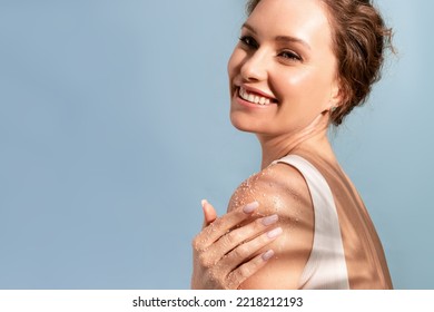 A beautiful tender woman put a natural cosmetic scrub to her shoulder and smiles