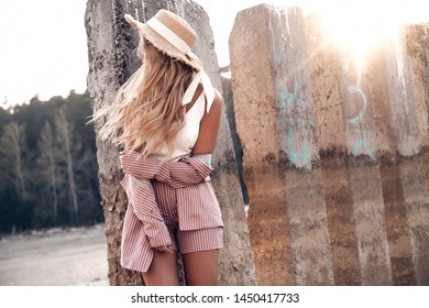 Beautiful tender young woman is posing in straw hat in the sunlight. Countryside landscape, forest nature at the background. Summertime, summer outdoor photo