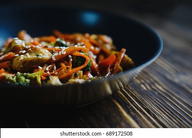Beautiful texture on wooden table frying pan wok with fried vegetables, meat, seafood, spices