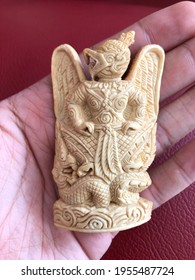 Beautiful Thai amulet close-up detail carved with a gouge from old ivory is Garuda with King of Nagas on hand blur background. Religious Buddhist amulets for protection safety for danger and good luck