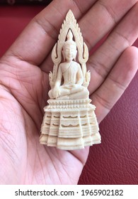 Beautiful Thai amulet close-up detail carved with a gouge from old ivory is Buddha on base over hand blur background. Religious Buddhist amulets for protection safety for danger and good luck