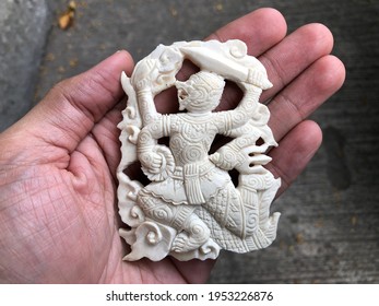 Beautiful Thai amulet Hanuman four arms and weapon closeup carved with a gouge from old ivory holder on hand blur background. Religious Buddhist amulets for protection form danger and Have a safe trip