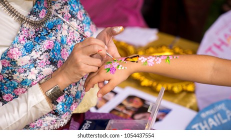 A Beautiful Thai woman in Thai transnational dress was painting kid's hand with paintbrush in Thailand Grand Festival in Sydney, 24-25/03/18. Australia 