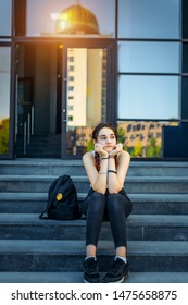 Beautiful Thoughtful Student Sitting On The Stairs Outdoors In Between Classes. Student Life, The Concept Of Education.