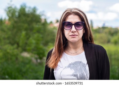 Beautiful But Tired And Sad Woman On Park Background In Her Hometown. A Woman Is Tired Of Problems At Work, Family, A Very Busy Schedule Of Life And Needs Rest And Peace In The Heart