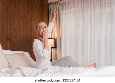 Beautiful Tired Senior Woman Yawning And Getting Ready For Sleep In Her Bright Modern Bedroom, Night Routine And Bedtime Concept