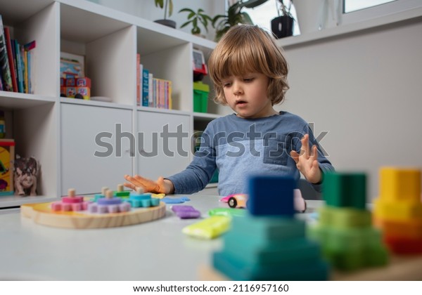Beautiful toddler sculpt a plasticine and play with a\
wooden toys at home. Toddler play with a color educational toy and\
wooden car. Child play at the table in the baby room. Funny baby.\
