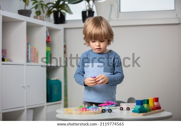 Beautiful\
toddler sculpt a plasticine and play with a wooden toys at home.\
Toddler play with a color educational toy and wooden car. Child\
play at the table in the baby room. Funny\
baby.