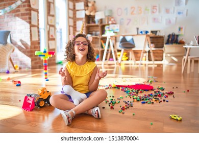 Beautiful Toddler Wearing Glasses And Unicorn Diadem Sitting On The Floor At Kindergarten Crazy And Mad Shouting And Yelling With Aggressive Expression And Arms Raised. Frustration Concept.