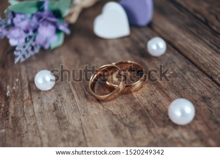 Beautiful toned picture with wedding rings lie on a wooden surface 