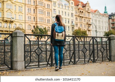 A Beautiful Tourist Girl With A Backpack Admiring The Ancient Architecture Of Prague In The Czech Republic. Tourism, Europe.