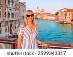 A Beautiful Tourist woman Standing on a Scenic Bridge in Venice During a Stunning Sunset View of Venices Grand Canal