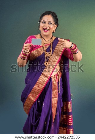 Beautiful traditional Indian woman wearing saree holding and posing with credit or debit card or blank business card