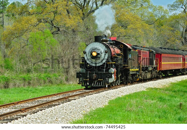 Beautiful train engine and cars on the track on\
a spring morning.