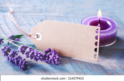 Beautiful tranquil spa and zen background with spikes of fragrant purple lavender and a burning aromatherapy candle on a rustic wooden background with a blank gift tag for your message - Powered by Shutterstock