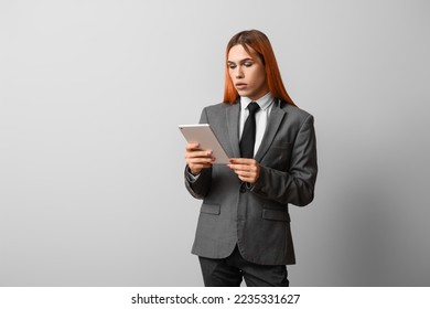 Beautiful transgender secretary with tablet computer on grey background