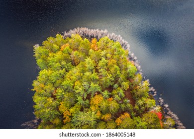 Beautiful travel autumn background aerial look down photograph of a portion of an island in a lake in Upper Michigan with fall foliage colors starting to show among the forest of evergreen trees.