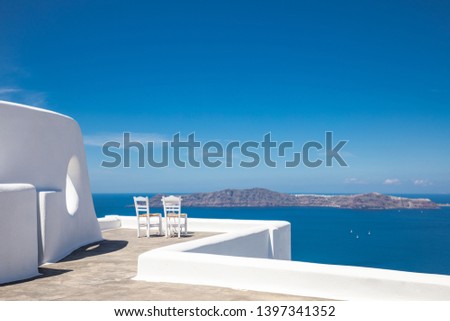 Beautiful travel background, two white chairs with white architecture on Santorini island, Greece. Luxury vacation scenery and summer holiday concept. Perfect tourism landscape, caldera with sea view