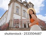 Beautiful traveler girl exploring the historic city of Salvador de Bahia. Young tourist woman smiling at camera in Largo do Bonfim square, Salvador, Bahia, Brazil.