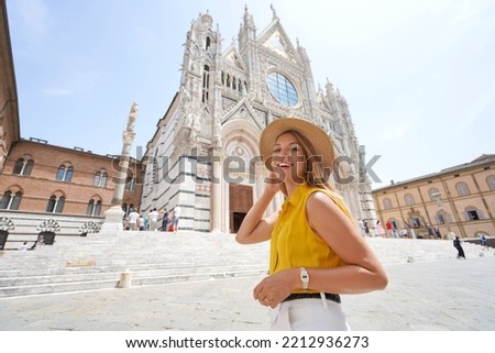 Beautiful traveler girl exploring the historic city of Siena in Tuscany. Young tourist woman smiling at camera in Siena Cathedral square, Tuscany, Italy.