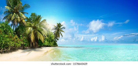 Красивый тропический пляж с белым песком, пальмами, бирюзовым океаном на фоне голубого неба с облаками в солнечный летний день. Идеальный ландшафтный фон для спокойного отдыха, остров Мальдивы.