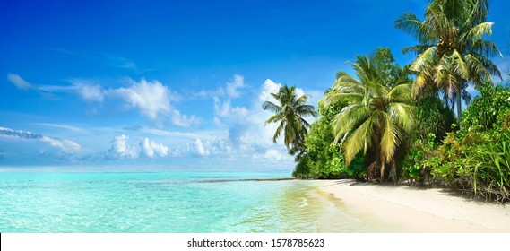 Красивый тропический пляж с белым песком, пальмами, бирюзовым океаном на фоне голубого неба с облаками в солнечный летний день. Идеальный ландшафтный фон для спокойного отдыха, остров Мальдивы.