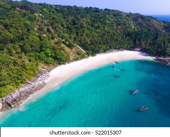 Beautiful tropical island with white sand beach and turquoise clear water, longtail boats and granite stones. Top view. Aerial shooting of Freedom beach, Phuket, Thailand.