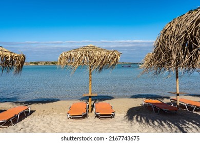 Beautiful Tropical Seascape. Beach Resort Hotel In Mediterranean Greece. Blue Sky And Sea. Horizon. Beach Umbrellas Are Covered With Palm Or Banana Leaves. Sun Loungers, Deck Chairs For Sunbathing. 