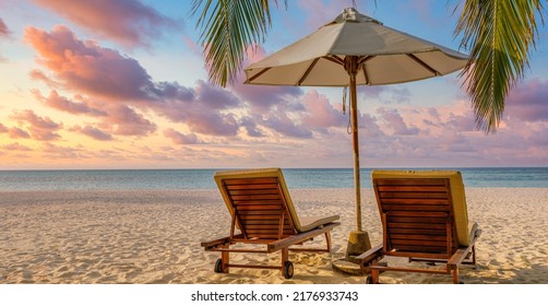 Beautiful tropical sunset landscape two lounge chairs, beds, umbrella under palm tree leaves. White sand sea view with horizon, colorful twilight sky, calmness and relaxation. Luxury beach destination - Shutterstock ID 2176933743
