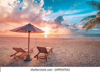 Beautiful tropical sunset scenery  two sun beds  loungers  umbrella under palm tree  White sand  sea view and horizon  colorful twilight sky  calmness   relaxation  Inspirational beach resort hotel