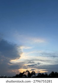 Beautiful twilight sky with dramatic clouds and palm trees silhouette during sunset.