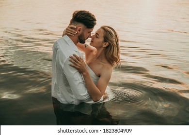 Beautiful two loving couple, man and woman romantically hugging and kissing in the lake at sunrise. Holidays at sea on the beach, sunset, morning, honeymoon, tropics, ocean, friend, relationship - Powered by Shutterstock