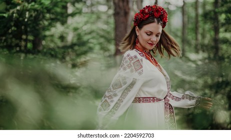 Beautiful ukrainian woman dancing in fir forest, Carpathian mountains nature. Girl in traditional embroidery vyshyvanka dress. Ukraine, freedom, ethnic national costume